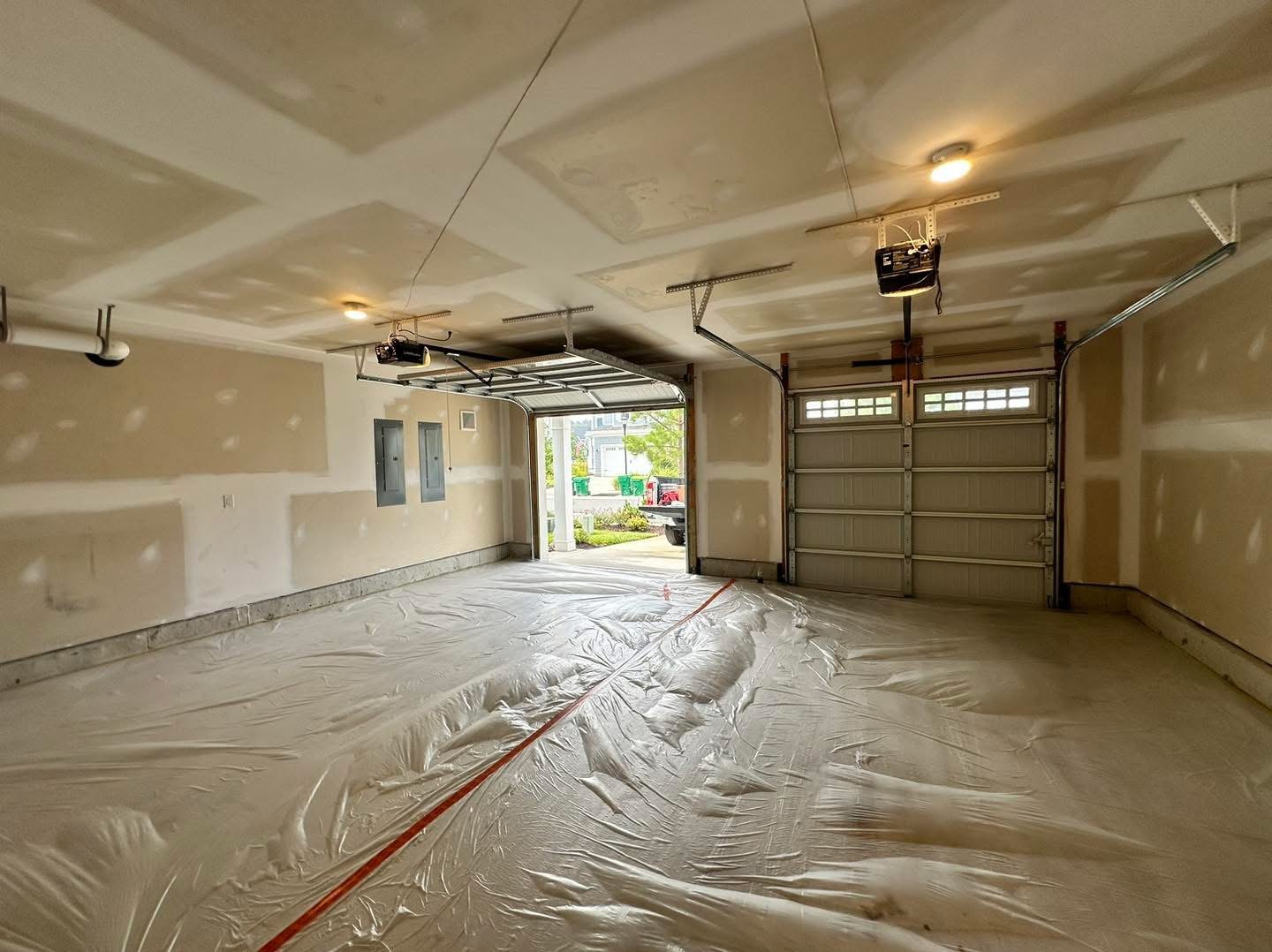 Residential garage during wall and ceiling preparation with floor protection